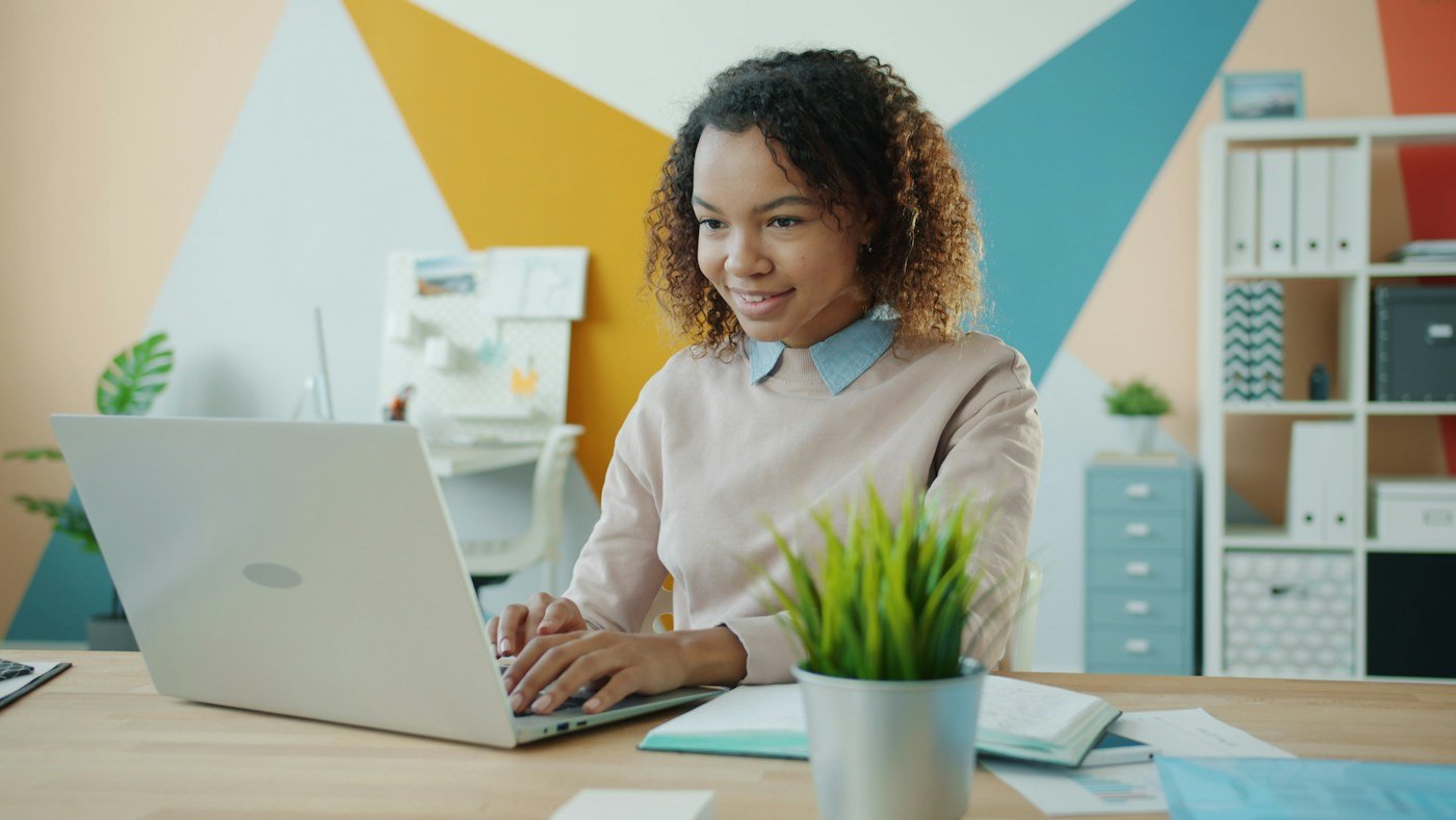 Woman smiling while using a laptop at a desk