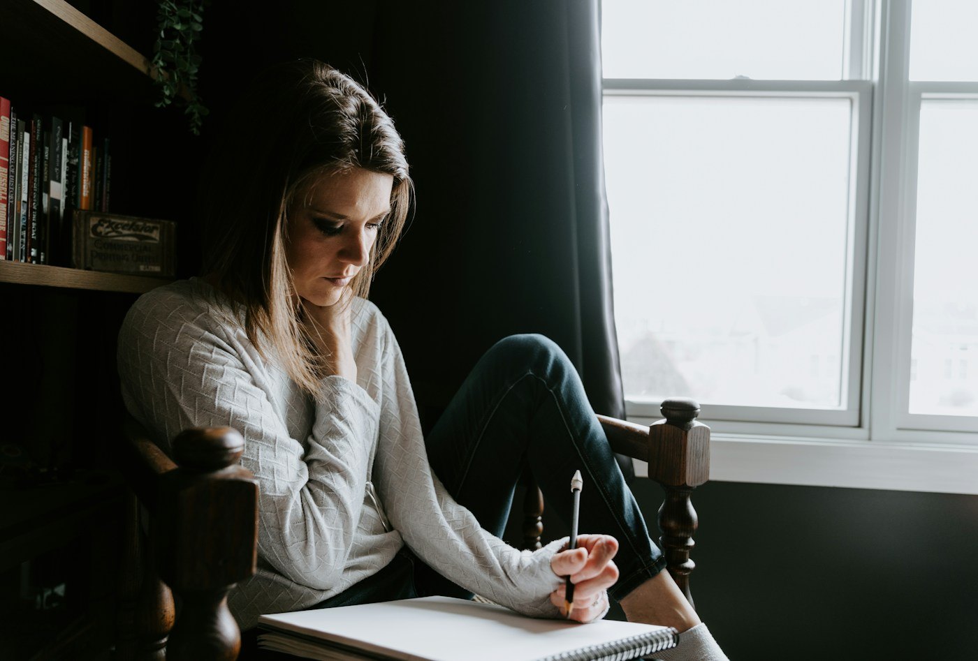 Woman writing in a notebook beside a window