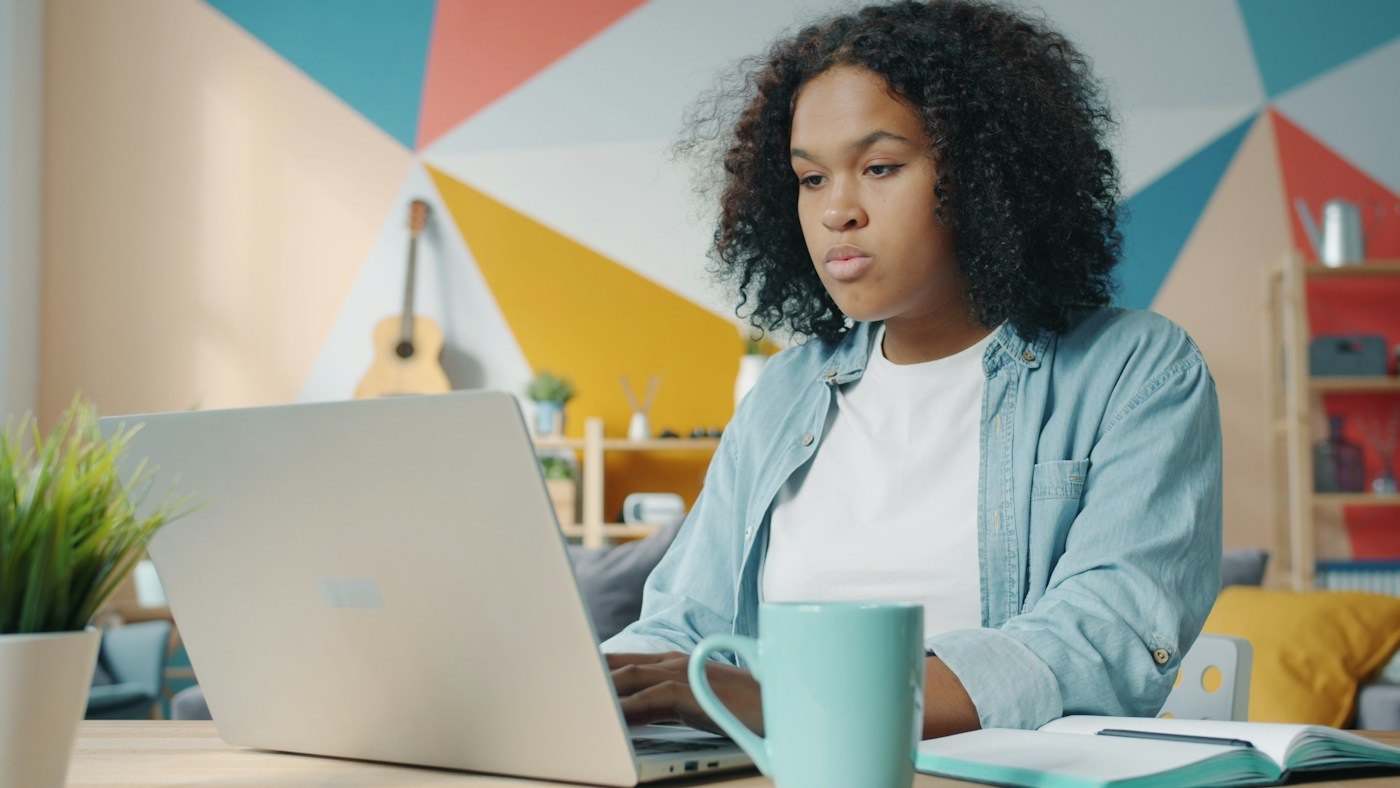 Woman working at a laptop with a mug beside her